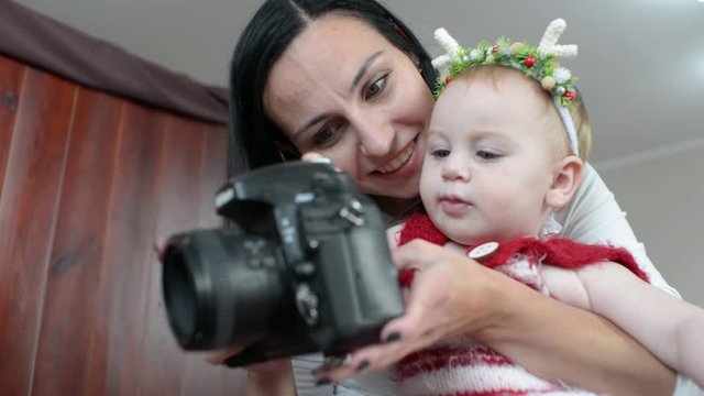 Cute little Baby Girl and Mother watch the Photos on Camera Nikon