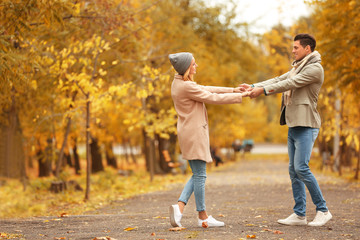 Young couple having fun in park on autumn day