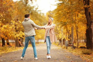 Young couple having fun in park on autumn day