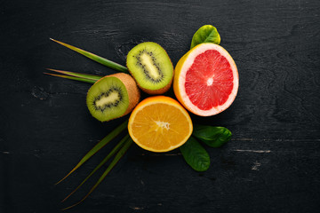 Kiwi, orange and grapefruit, fresh fruits. On a wooden background. Top view. Free space for text.