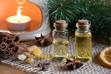 Fototapeta na wymiar Two bottles of essential oil with cinnamon, star anise, frankincense and an aroma lamp