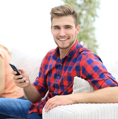 modern guy with a smartphone and his friends sitting on the couch