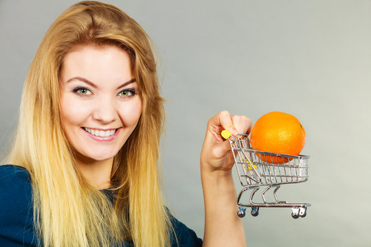 Woman holding shopping cart with orange inside