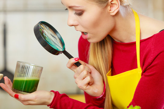 Woman Looking At Green Juice Through Magnifer