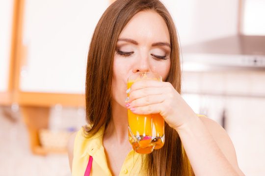 Woman in kitchen drinking fresh orange juice