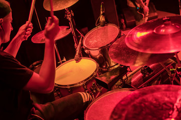 Drummer beats the drums at a concert in red light