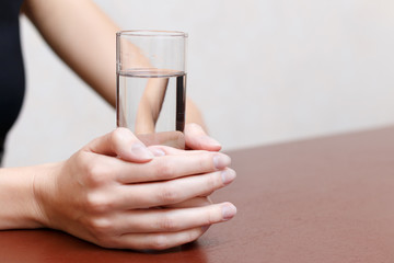 Girl holding a glass of water standing on the table..