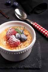 Creme brulee with berries on dark stone