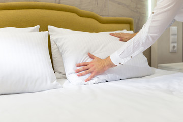 Obraz na płótnie Canvas hotel staff setting up pillow on bed