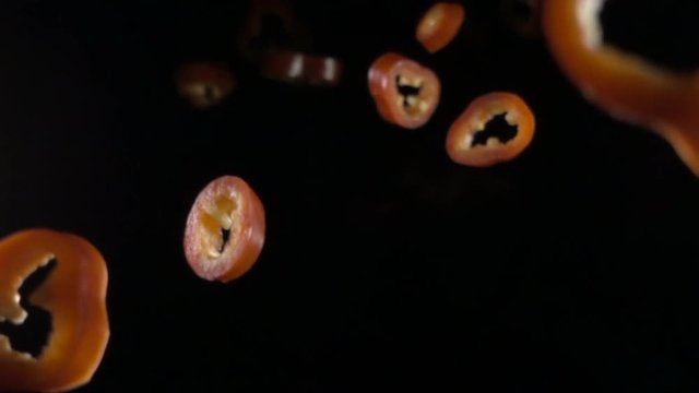 Creative concept with flying red paprika. Sliced floating pepper isolated. Levity capsicum vegetable isolated on black background. macro