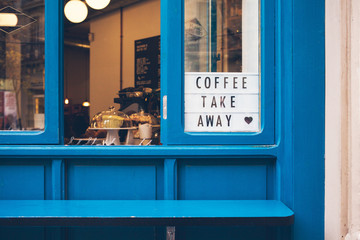 Blue color window of a cafe offering take away specialty coffee to go and food to take out. Ordering food concept 