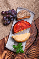 Cheese and grapes on pottery plate on old wooden table
