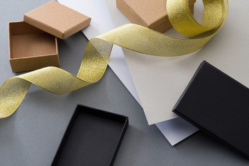 Empty brown gift boxes and gold ribbon on gray background. Gift wrapping. Preparing ornaments.