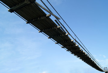 view from below on an old wooden suspension bridge on a sky background