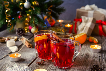 Christmas mulled wine, Hot winter drink with berries, orange,spices, cinnamon in glass cups on the old wooden table with gift boxes, Fir branches, decor, candles. vintage background, Selective focus