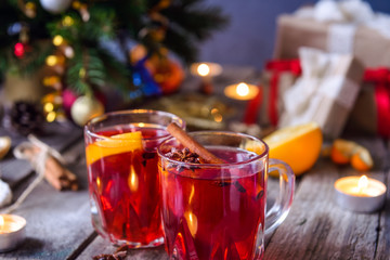 Christmas mulled wine, Hot winter drink with berries, orange,spices, cinnamon in glass cups on the old wooden table with gift boxes, Fir branches, decor, candles. vintage background, Selective focus