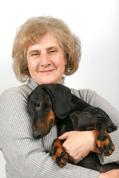 Elderly woman sits and embosom dachshund 