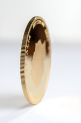 The gold coin stands vertically.