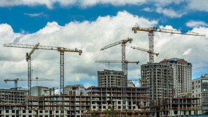 Fototapeta premium construction of a new residential city block with liftable crane against the blue cloudy sky