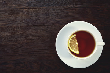 white cup of tea with cookies on a wooden background