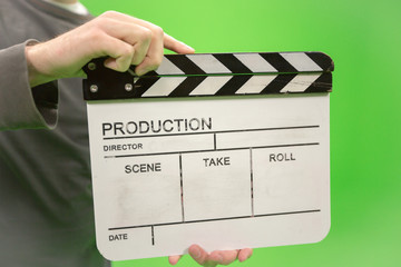 Video producer man holding movie clapper board on green background