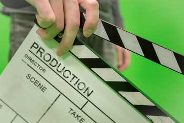 Video producer man holding movie clapper board on green background