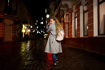 Girl with dreadlocks walking at night street of city.