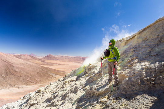 Tourist adventurer backpacker standing smoking volcano mountain peak, Bolivia.