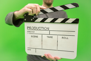 Video producer man holding movie clapper board on green background