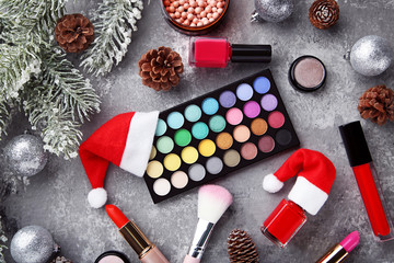 Makeup cosmetics with christmas baubles and fir-tree branch on wooden table