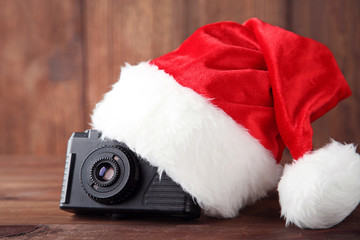 Obraz na płótnie Canvas Red santa hat with retro camera on grey wooden table