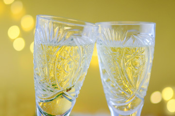 New Year's composition: Two glasses with champagne on a gold background.