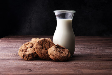 Chocolate chip cookies with milk on rustic wooden table