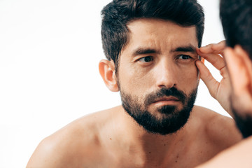 Man in front of mirrror looking at his wrinkles