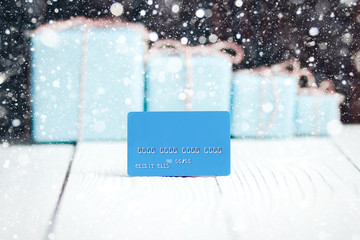 Christmas New Year composition blue credit card with gifts on background, sell discounts buy concept with place for text on white wooden table background banner web design soft  drawing snowfall