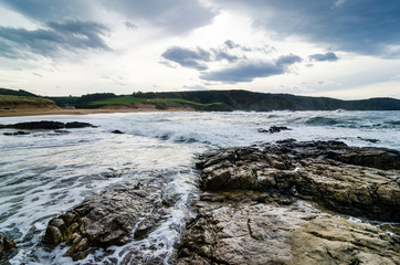 Waves on the coast in Verdicio beach in Asturias, Spain.Choppy sea in a virgin beach with rocks and foam at evening