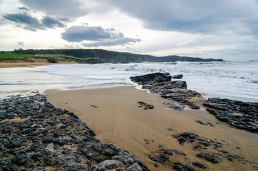 Waves on the coast in Verdicio beach in Asturias, Spain.Choppy sea in a virgin beach with rocks and foam at evening