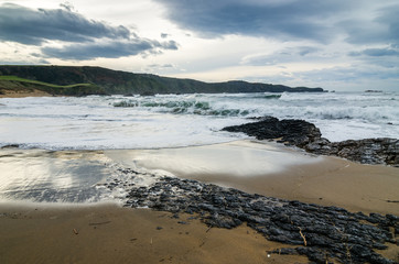 Waves on the coast in Verdicio beach in Asturias, Spain.Choppy sea in a virgin beach with rocks and foam at evening