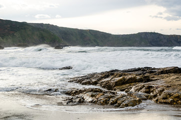 Waves on the coast in Verdicio beach in Asturias, Spain.Choppy sea in a virgin beach with rocks and foam at evening