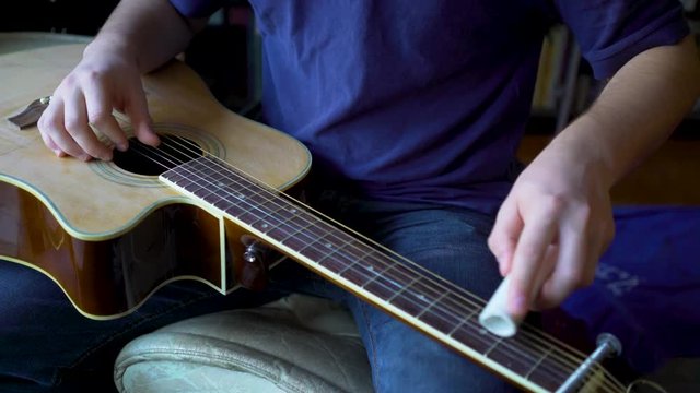 Closeup of a musician playing a slide guitar with a pvc section of pipe.