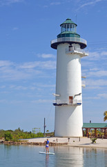 Faux lighthouse tower used as a zip line station and a woman on a paddle board in a lagoon on an island leased by a cruise line off the coast of Belize