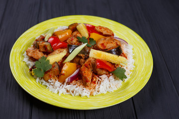 Delicious Pan-Asian food, appetizing spicy rice with chicken, pineapple slices and vegetables on bright plate, close up. Pan-Asian, thai food, oriental cuisine
