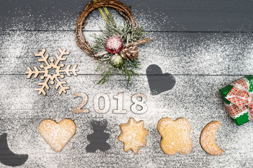 2018 numbers and christmas different shaped cookies with sugar powder and wooden snowflake on wooden table