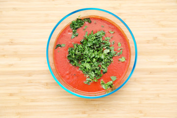 Home made fresh and quick spicy red Enchilada Sauce in a glass bowl with Cilantro garnishing on top.Sauuce in a glass bowl.Ready to use Sauce.Top view picture of sauce