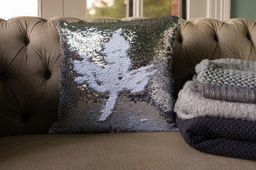sofa with sequin cushion with leaf motif, and warm winter rugs