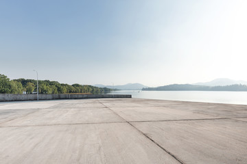 empty concrete floor with beautiful lake in blue sky