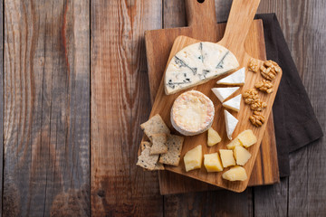 Tasting cheese dish on a wooden plate. Food for wine and romantic, cheese delicatessen on a wooden...