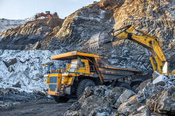 Big yellow dump truck and excavator in the coal mine, fisheye

