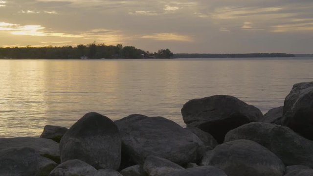 static shot of the distant shore of lake Simcoe, from the rocky shore at sunset