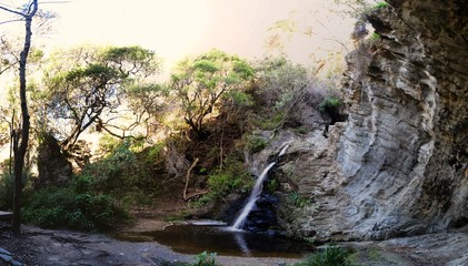 Sun setting behind waterfall at Storms River Mouth, Tsitsikamma, South Africa